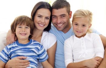 Smiling family with two kids sitting on the couch