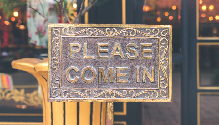 Bronze sign saying Please Come In encouraging new patients to come to Three Creek Dentistry