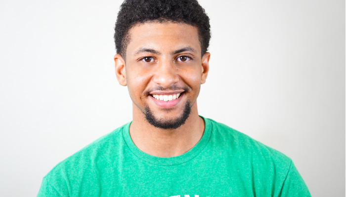 Brunette man wearing a green T-shirt smiles after straightening his teeth using Invisalign clear aligners