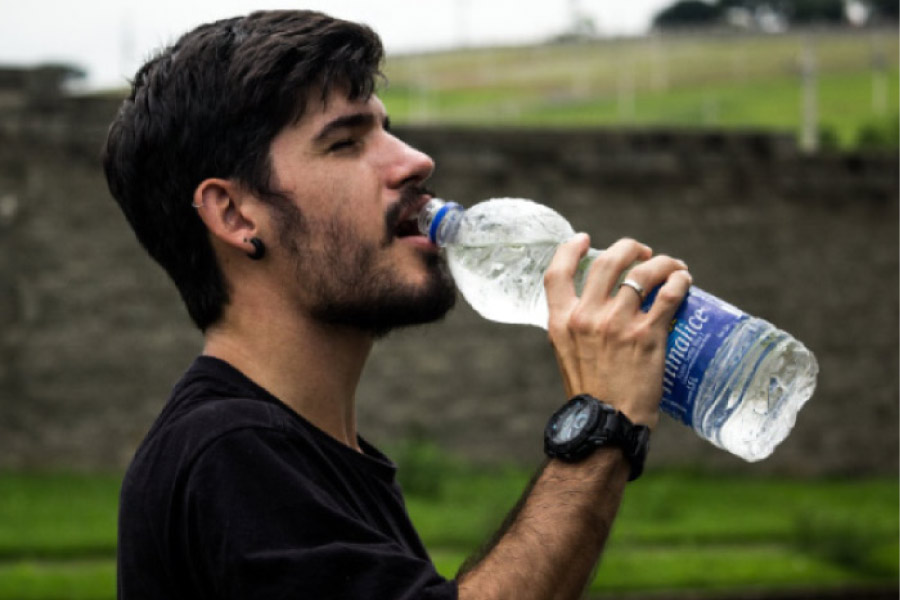 man drinking a big bottle of water to reduce dental plaque